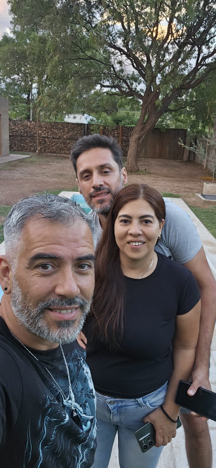 Sergio junto a Marcelo y Rosina, al aire libre entre árboles.